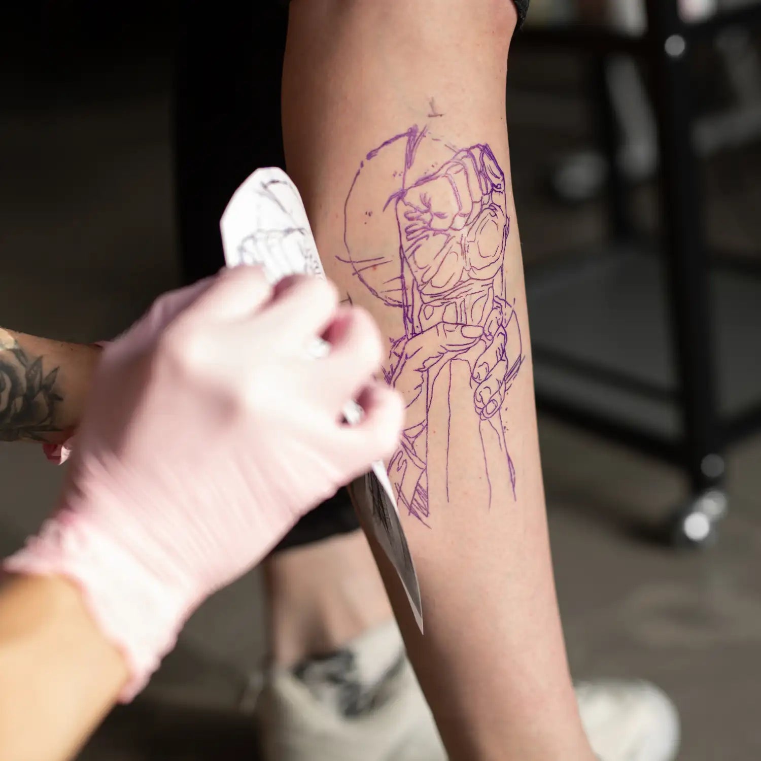 Person getting a tattoo of a robot design on their arm.