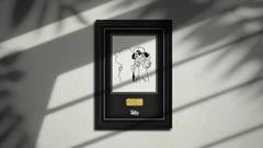 Framed black and white illustration with a gold label on a gray wall